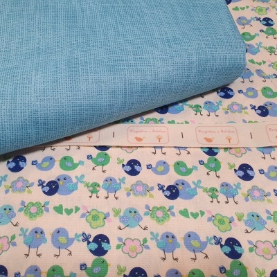 Tecido estampado com pássaros, baleias e flores ao lado de tecido azul liso