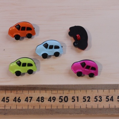 Botões em forma de carro coloridos sobre madeira com régua