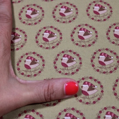 Tecido com padrão de corações e pássaros em fundo verde claro e mão com unha vermelha