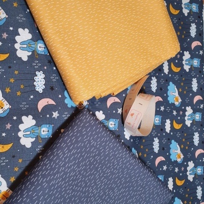 Tecidos infantis com padrões de nuvens, estrelas e ursinhos, e tecidos amarelo e azul com pequenos traços brancos