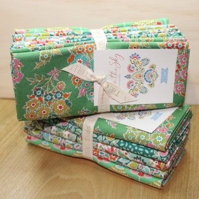 Conjuntos de tecidos florais verdes amarrados com fita e etiqueta, sobre madeira