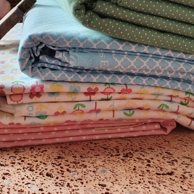 Quatro mantas dobradas com diferentes padrões e cores em superfície de pedra