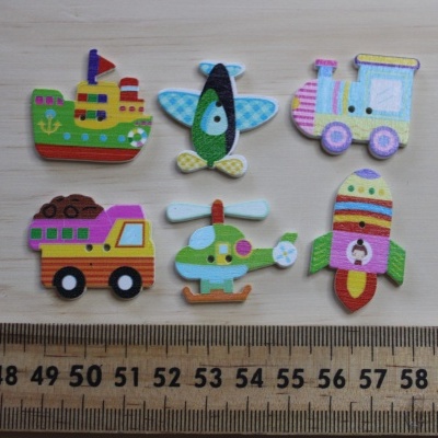 Ímanes pequenos de transporte em madeira pintada sobre mesa clara próxima a régua.