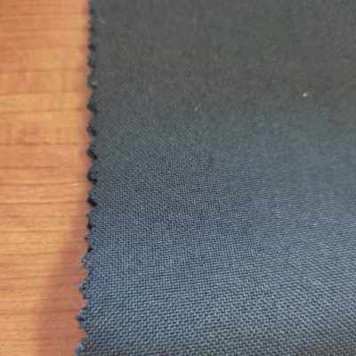 Tecido preto com borda recortada em ziguezague sobre madeira clara