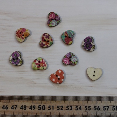 Botões de madeira em forma de coração com padrões florais coloridos sobre superfície de madeira com régua