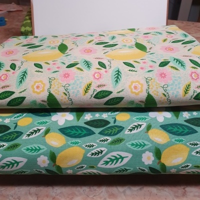 Dois panos de tecido com padrão de limões, folhas e flores, um bege e outro verde.