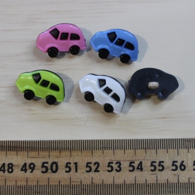 Botões coloridos em forma de carros sobre madeira ao lado de régua