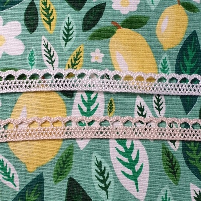 Dois pedaços de renda cor de rosa claro sobre tecido estampado de limões, folhas e flores