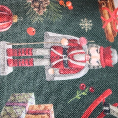 Estampa de tecido natalício com soldadinho de chumbo, presentes e enfeites em fundo verde