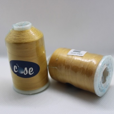 Dois carretéis de linha dourada, um em pé com etiqueta azul 'cose' e outro deitado com etiqueta branca 'DUPLO 100% POLYESTER 150m' em fundo branco