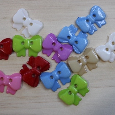 Botões coloridos em forma de laço sobre superfície de madeira clara