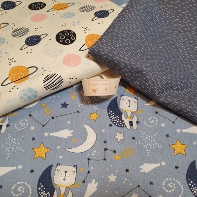 Três tecidos infantis com padrões de planetas, estrelas e traços brancos