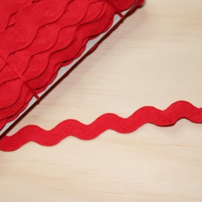 Fita vermelha ondulada sobre madeira clara