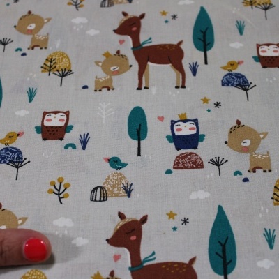Tecido bege com padrão infantil colorido de animais e árvores