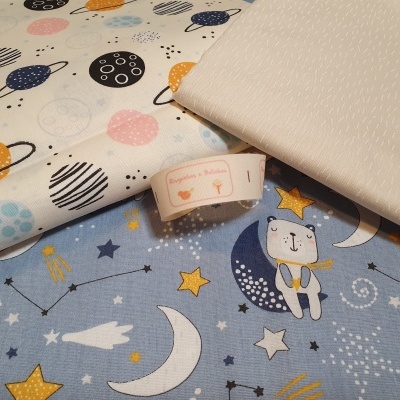 Três tecidos com padrões de planetas, estrelas, urso e texturas diversas