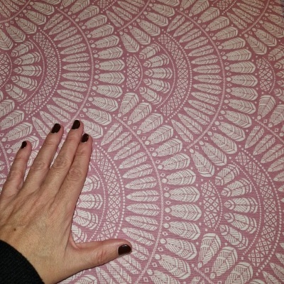 Tecido rosa com padrão circular branco e mão com unhas pintadas castanho escuro