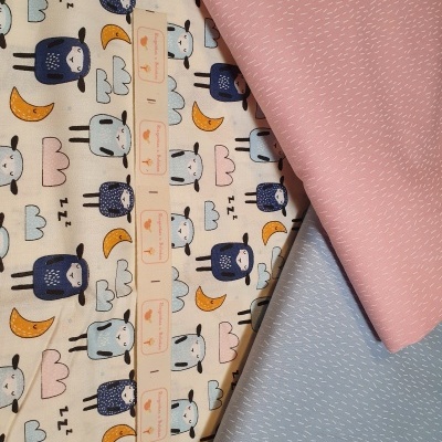 Três tecidos com padrões distintos: corujas, nuvens e luas, rosa com traços brancos e azul-claro com traços brancos.