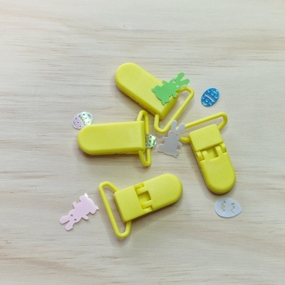 Pregadores de plástico amarelos com figuras coloridas em madeira clara