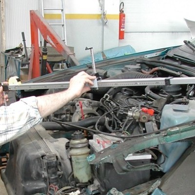 Homem a medir motor de carro verde numa oficina