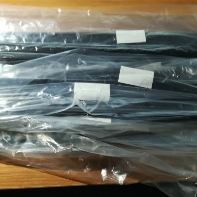 Peças pretas embaladas em sacos plásticos transparentes sobre mesa de madeira