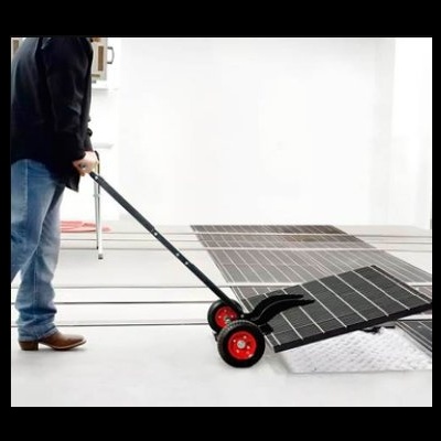 Pessoa a transportar painéis solares pretos com carrinho de mão