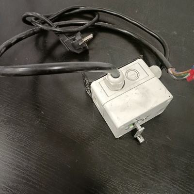 Caixa elétrica branca com fios e cabo preto sobre superfície preta