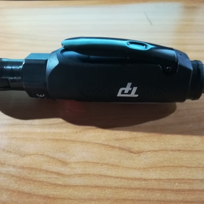 Chave de catraca pneumática preta com botão vermelho sobre madeira