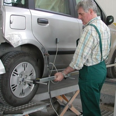 Homem a ajustar alinhamento de rodas de carro cinzento numa oficina mecânica