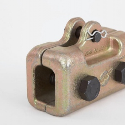 Peça metálica industrial dourada com parafusos pretos e pino de segurança