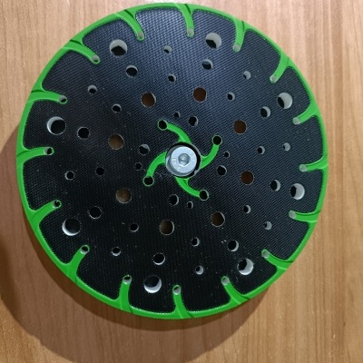 Placa de lixagem circular preta com borda verde sobre madeira