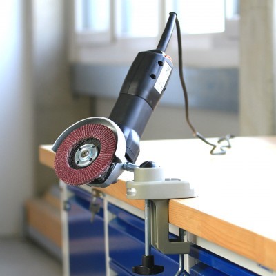 Lixadora elétrica preta com disco abrasivo vermelho fixada numa bancada azul