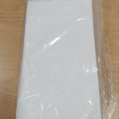 Toalha ou tecido branco embalado em plástico sobre mesa de madeira.