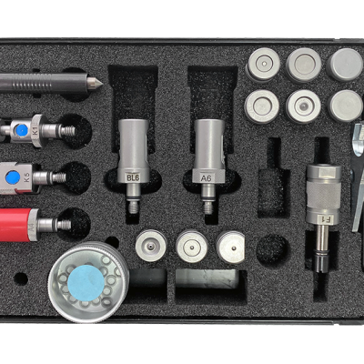 Conjunto de ferramentas metálicas e plásticas organizadas em espuma preta numa caixa preta.