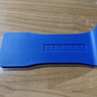 Ferramenta plástica azul com inscrição STRAIGHT sobre mesa de madeira clara