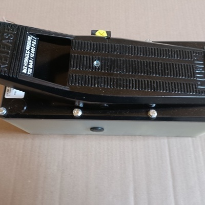 Pedal eletrónico preto com etiquetas de texto branco sobre superfície de cartão