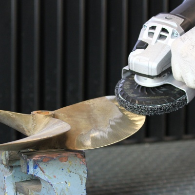 Máquina de polir a polir uma hélice metálica dourada numa bancada