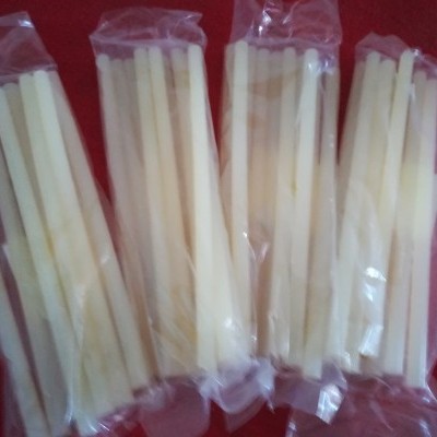 Quatro pacotes com palitos cilíndricos cremes sobre fundo vermelho