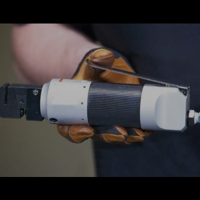 Ferramenta elétrica portátil com superfície branca e preta segurada por mão com luva