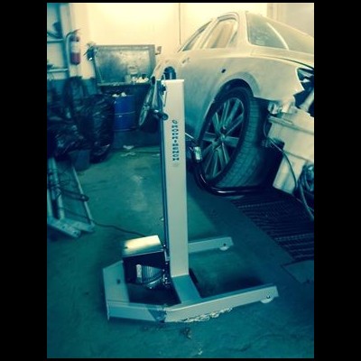 Suporte metálico branco com texto 'DIGITAL 1047' em oficina com carro branco ao fundo