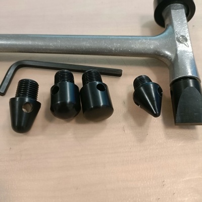 Conjunto de martelo metálico e peças roscadas pretas sobre mesa de madeira clara