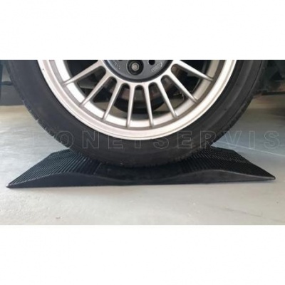 Roda de carro sobre cunha de borracha preta no chão cinza