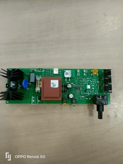 Placa eletrónica verde com componentes incluindo dissipadores, bloco vermelho com etiqueta, resistores, condensadores e potenciômetro preto