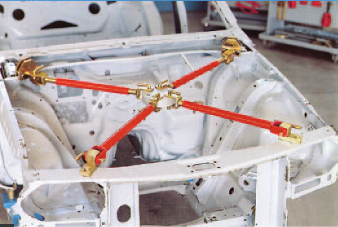 Estrutura metálica branca com barras vermelhas e ligações douradas em oficina