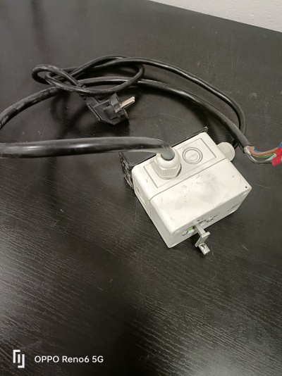 Caixa elétrica branca com fios e cabo preto sobre superfície preta