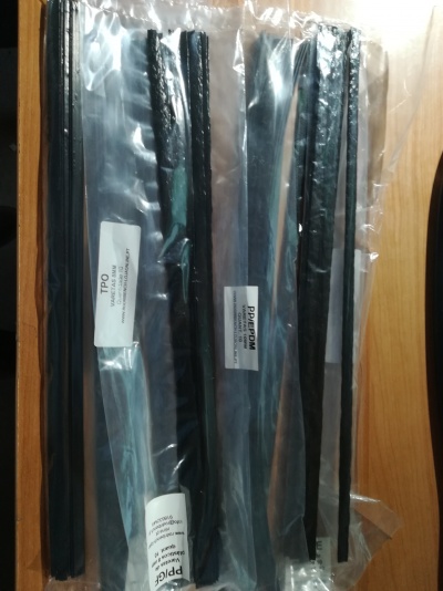 Tiras negras embaladas em plástico com etiquetas sobre mesa de madeira