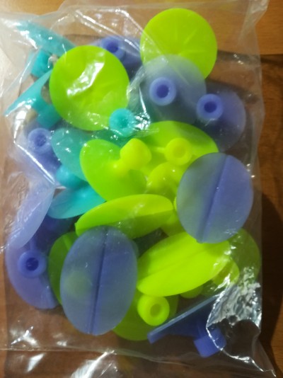 Pacote com ventosas de plástico verde e roxo sobre madeira