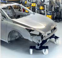 Estrutura metálica prateada de carro em oficina automóvel, base móvel preta com rodas brancas