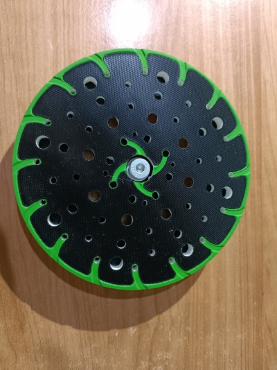 Placa de lixagem circular preta com borda verde sobre madeira