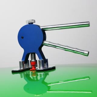 Prensa manual azul com alavancas metálicas sobre superfície verde