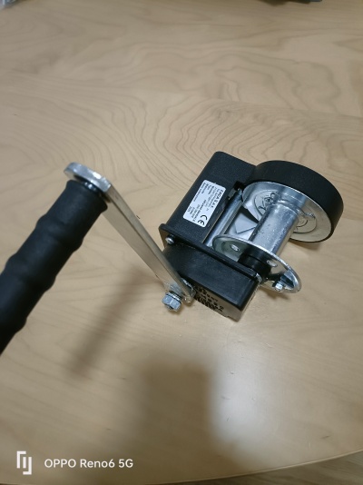 Manivela metálica com punho preto e roda em metal e borracha